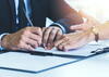 a woman helps out a man by pointing out where to sign on a document